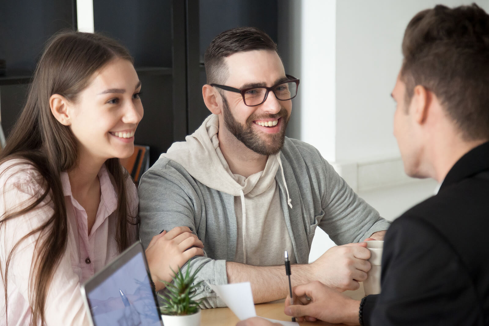 Millenial couple discussing mortgage loans with a mortgage advisor.