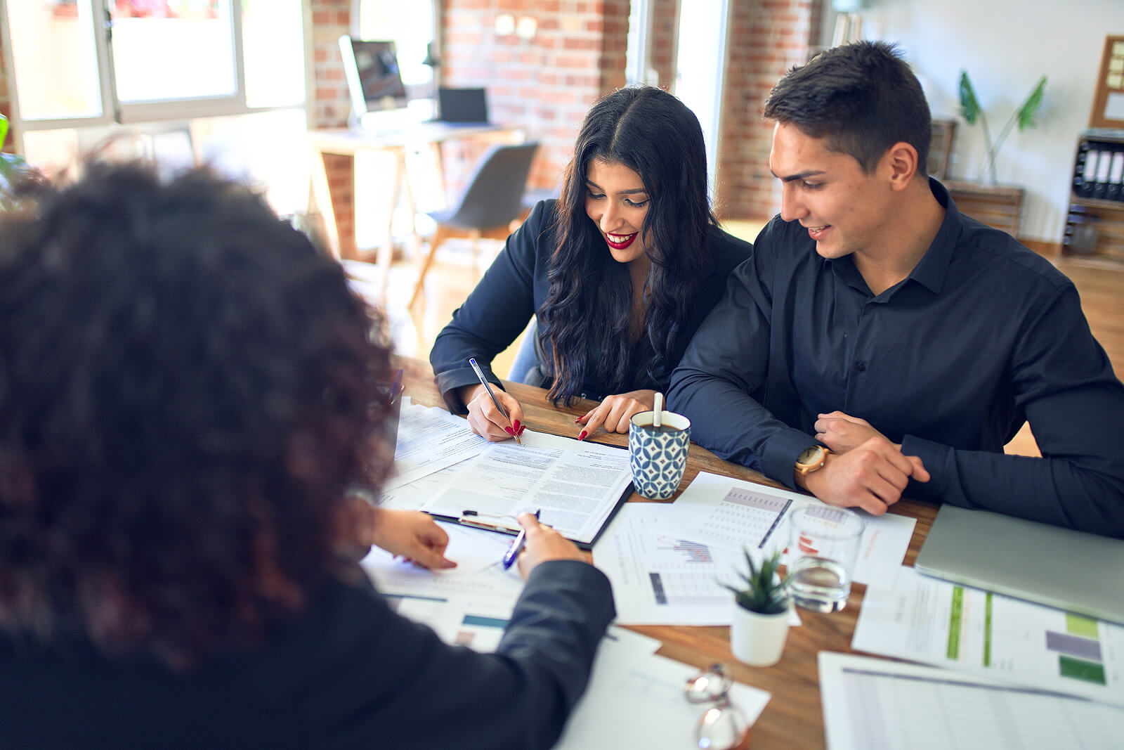 A happy couple signing mortgage loan papers at a bank.