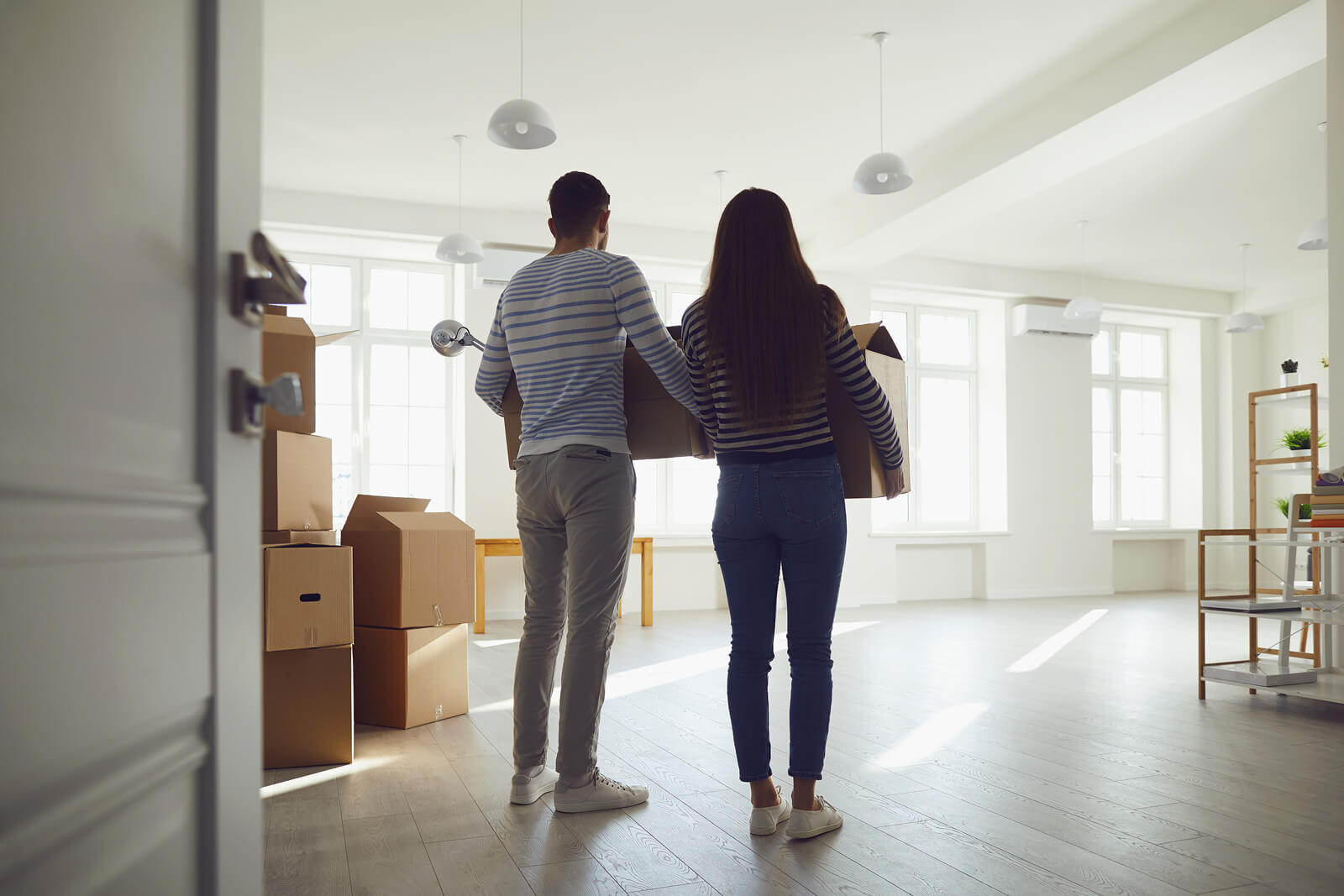 A young couple looks at an empty room in the house they bought with a mortgage loan.