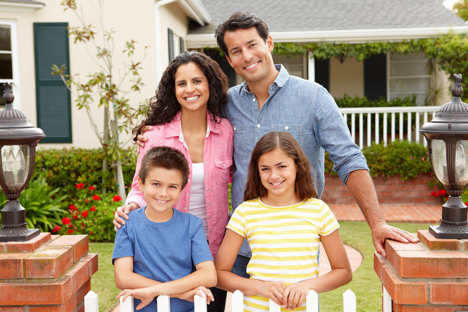 A family stands and smiles in front of their new house.