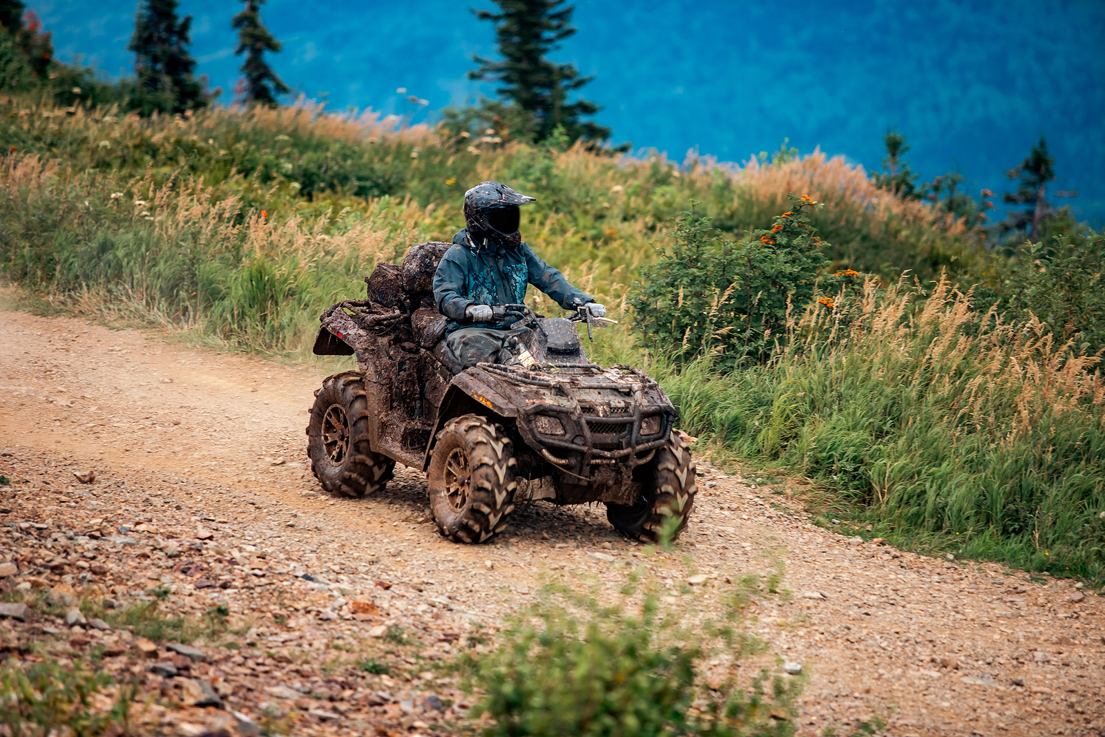 an ATV rider is riding on a dirt trail wearing a helmet.