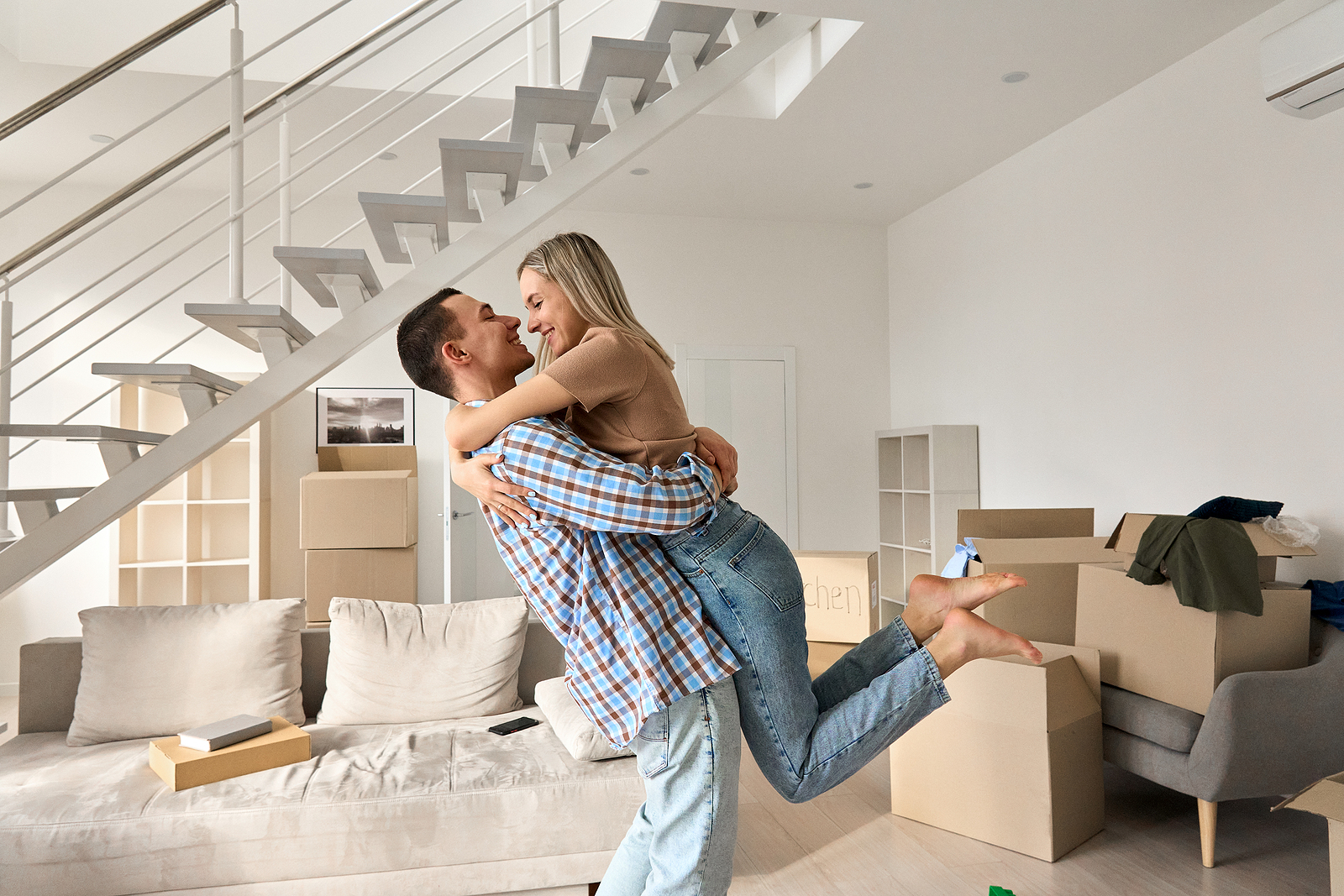 a happy couple surrounded by boxes, hug each other on their moving day.