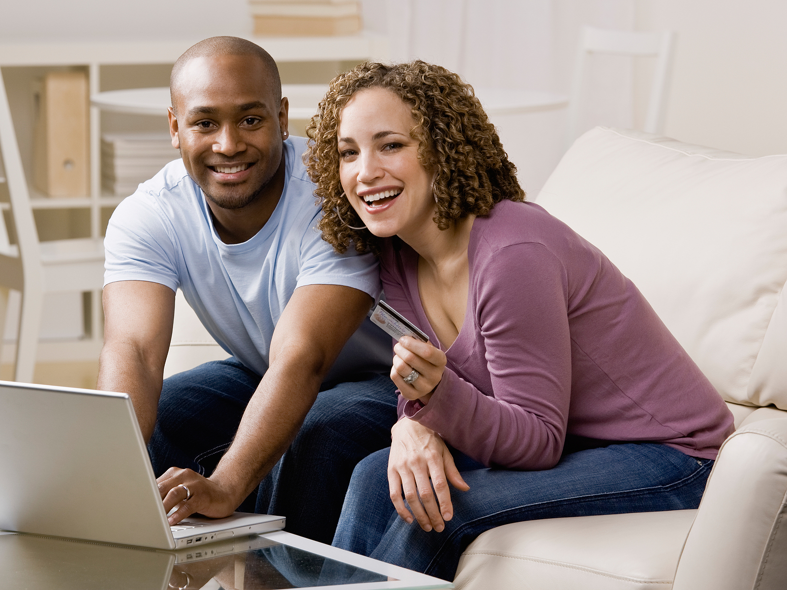 a man and woman smile as they shop with a credit card online.