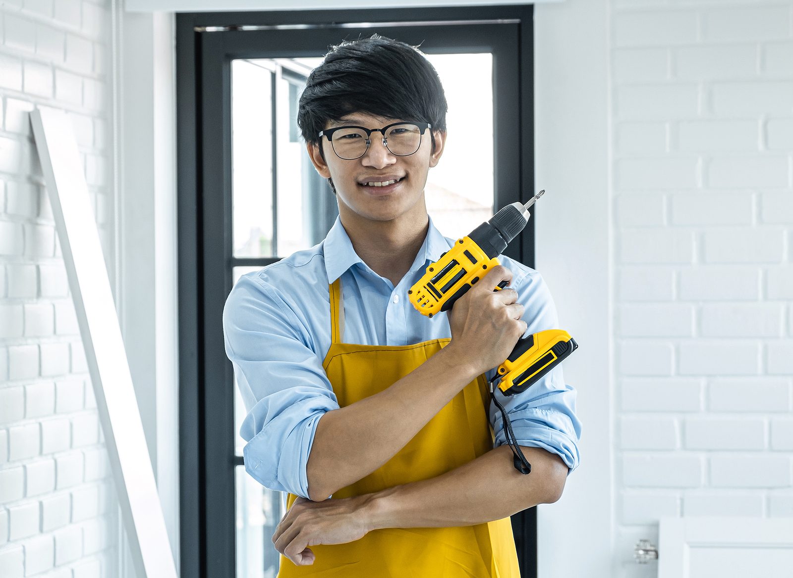 a young man hold a drill as he begins a home improvement project.