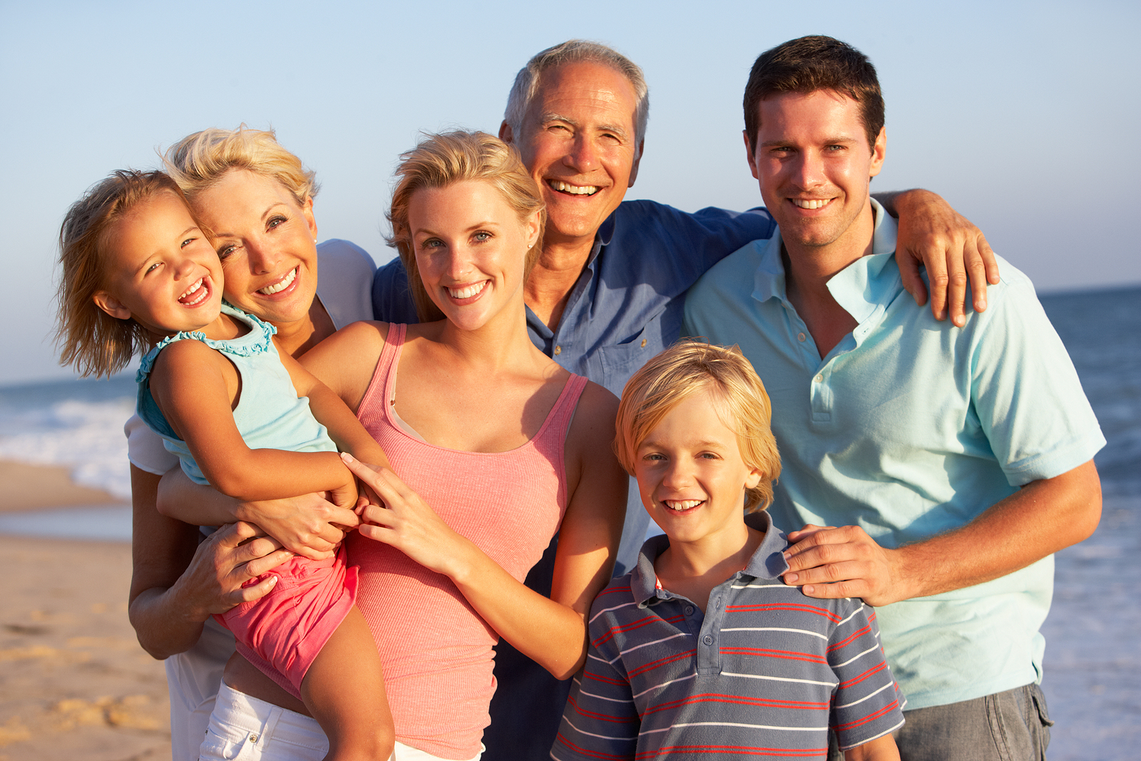 a happy family of parents, grandparents, and children are on the beach on vacation.