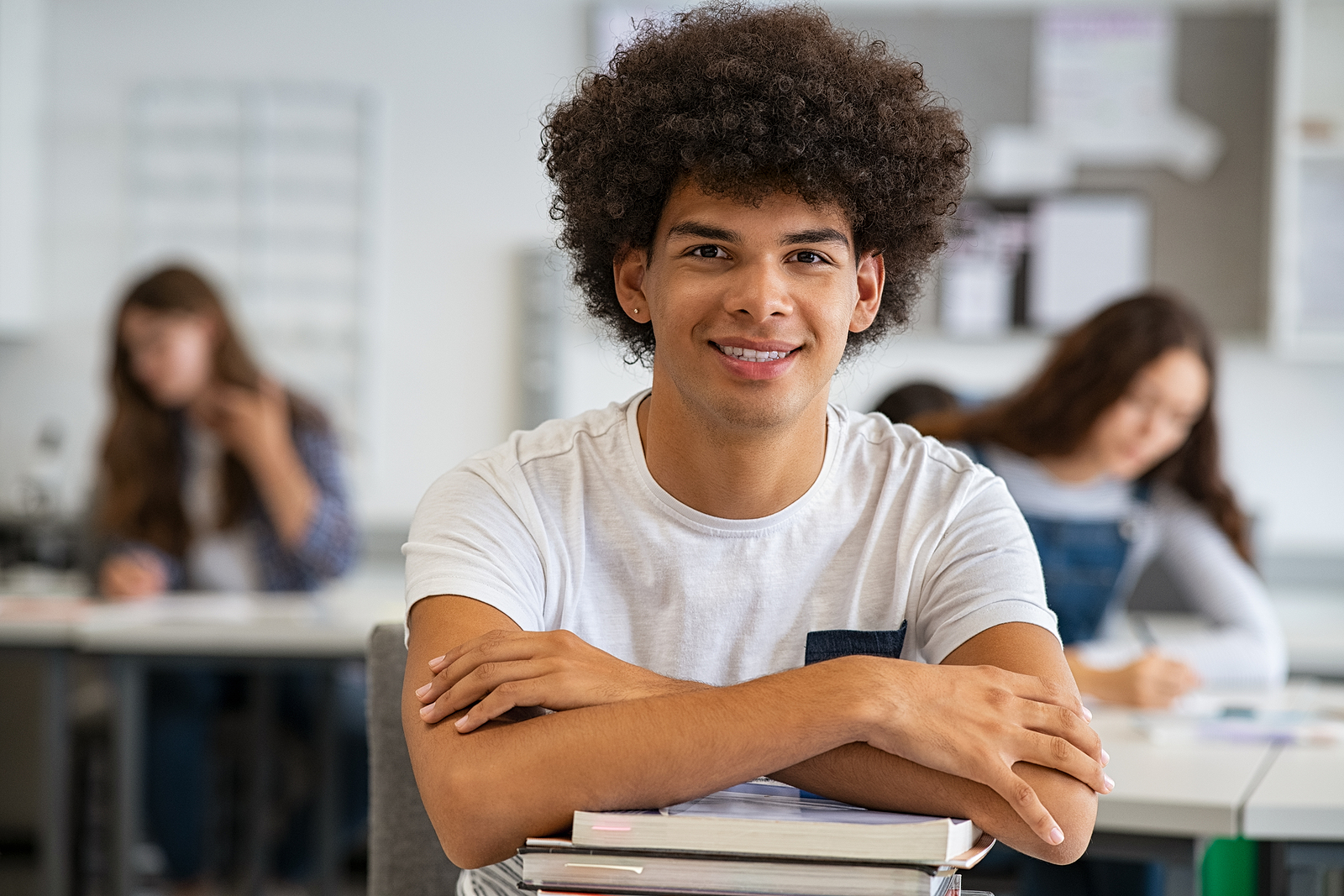 a smiling young man sits in a college class.