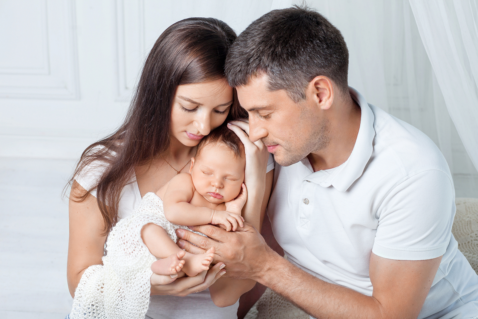 a man and lady cradle their newborn infant.