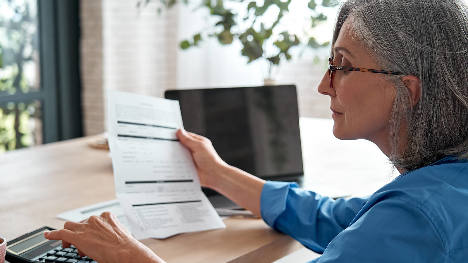 A woman manages her finances on a calculator to determine if a personal loan is the right next step.