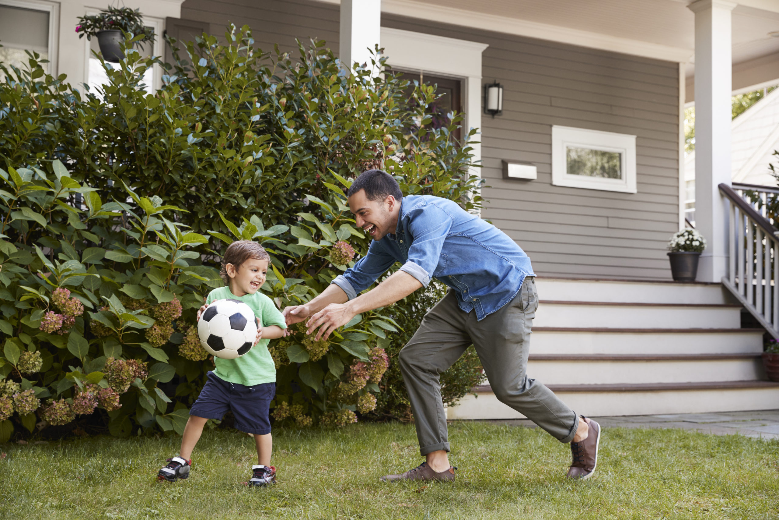 A father and son play in the yard of their home after refinancing.