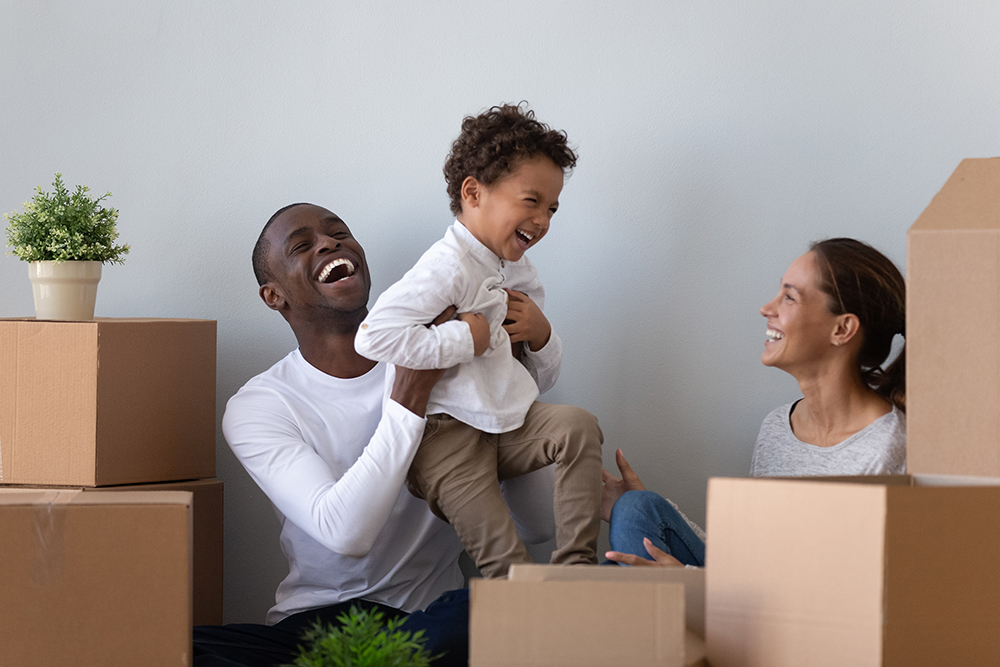 A family laughs as they unpack in their new home after learning about buying a first home.