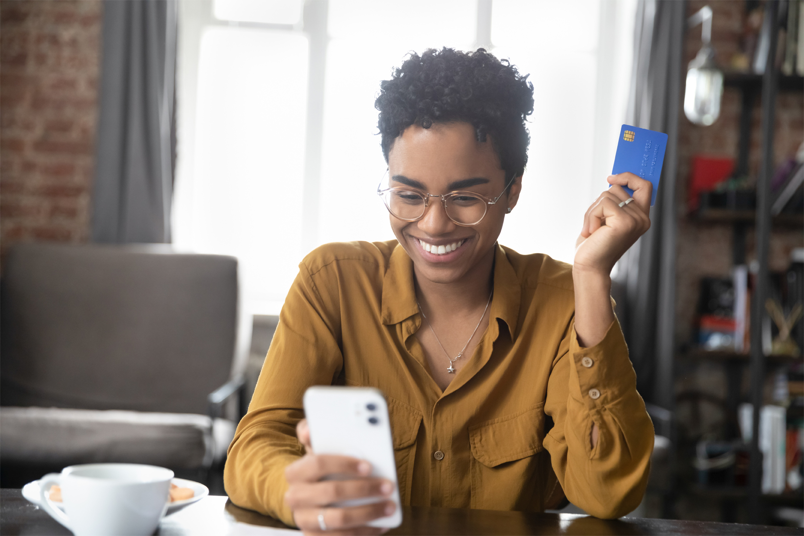 A young woman holds her credit card and smartphone as she reviews the benefits of a balance transfer.