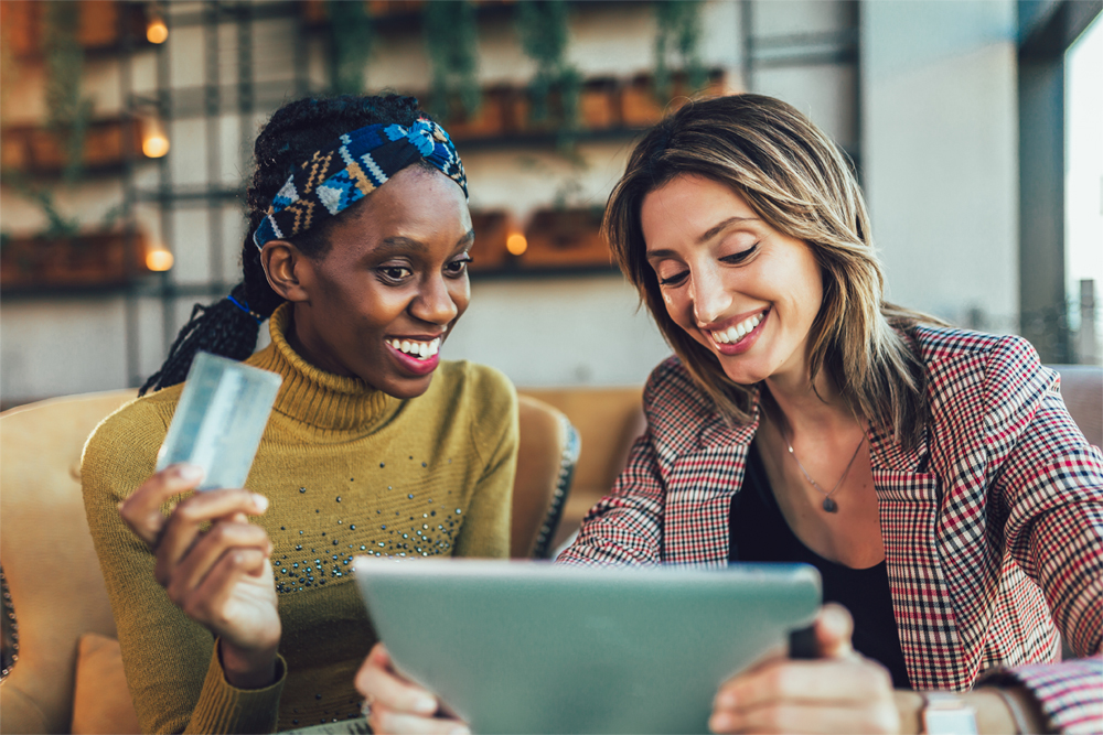 Two women discuss a new credit card purchase after paying off their credit cards faster.