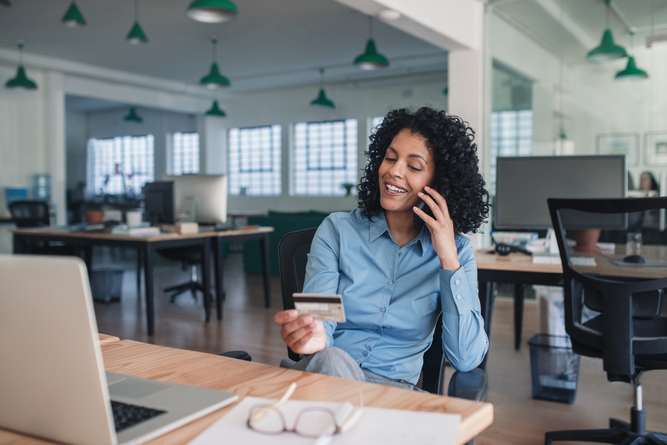 A woman looks at her laptop and credit card and considers a balance transfer.