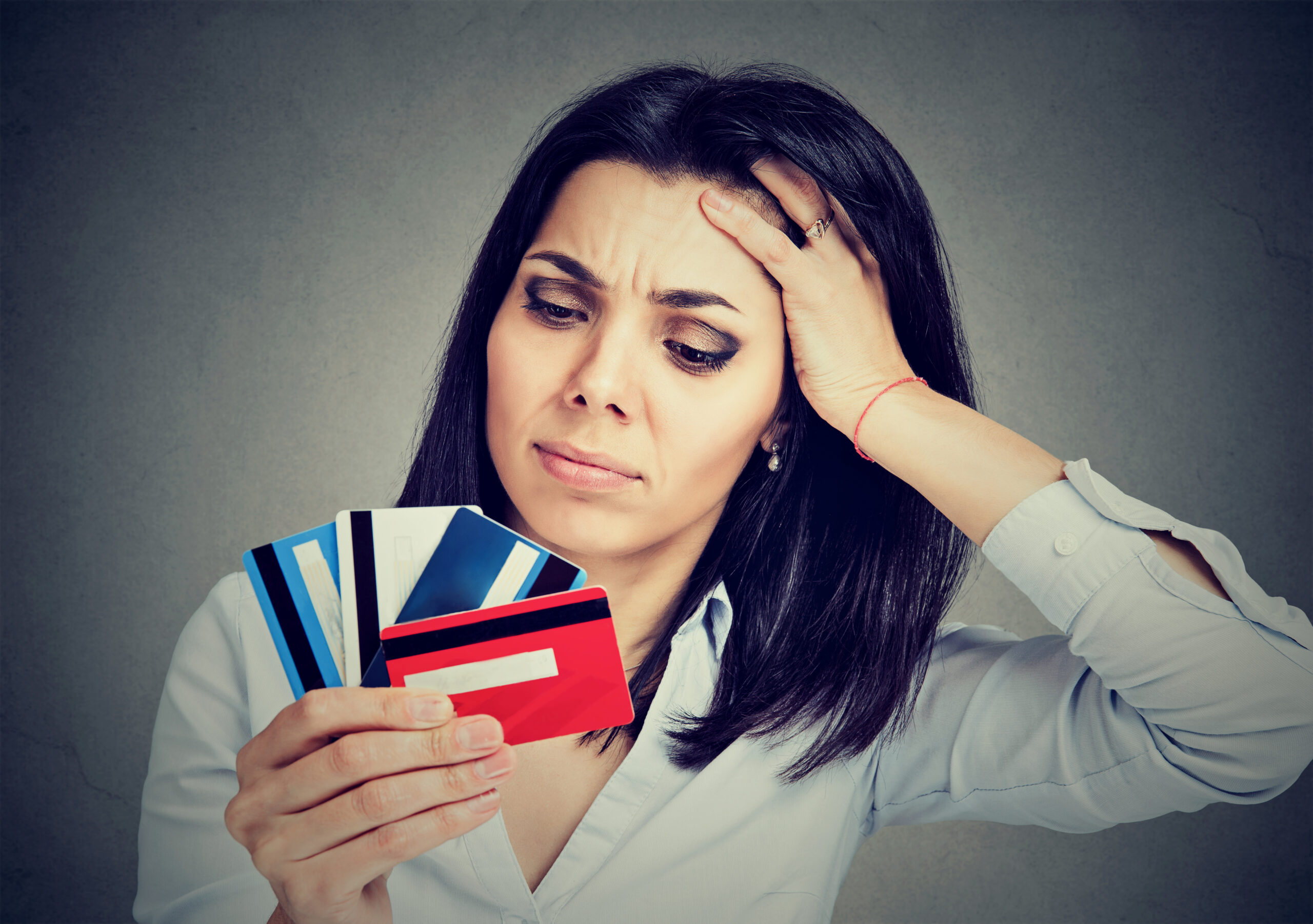 A woman holding several credit cards wondering how many credit cards is too many?