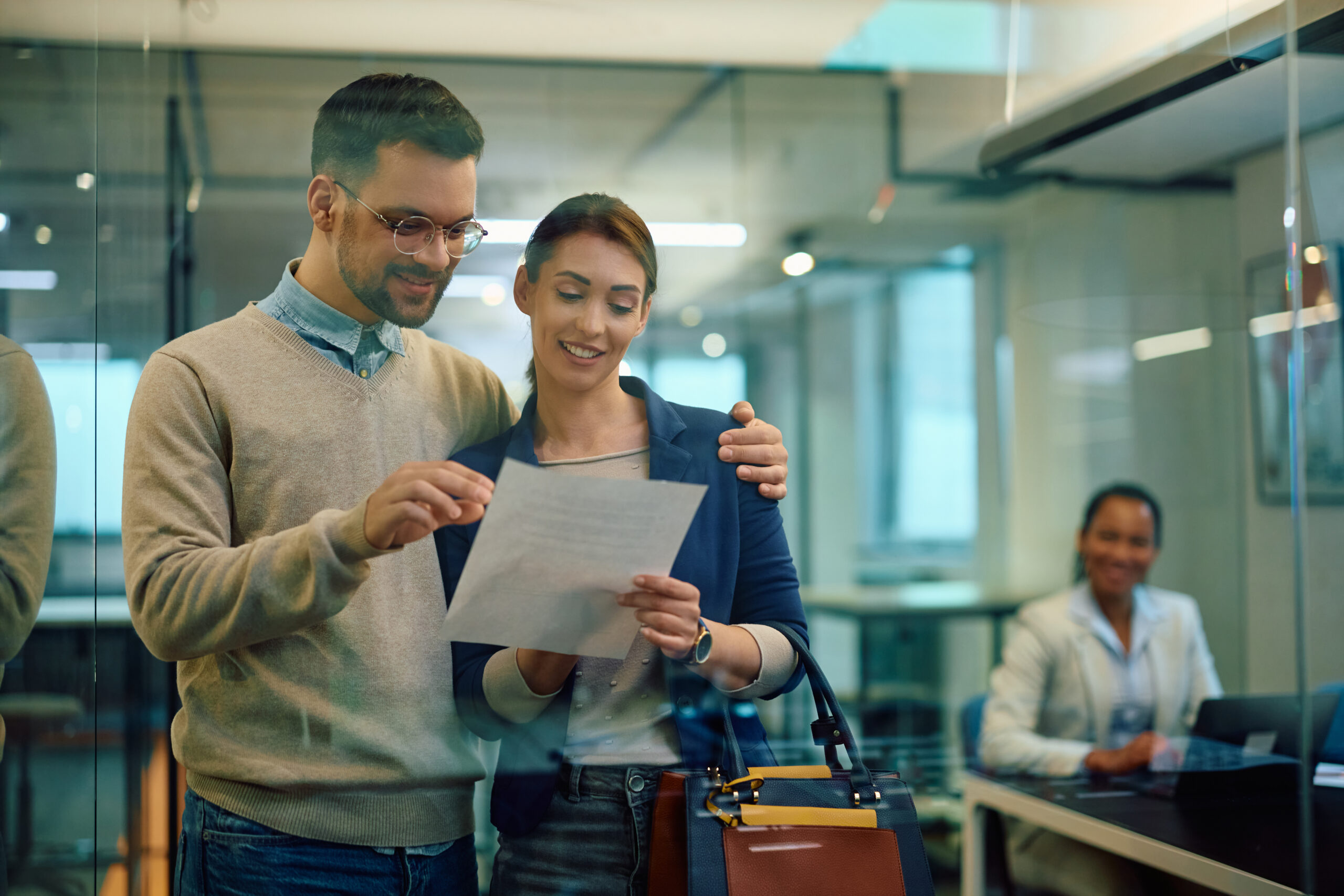 Man and wife smiling inside Bowater Credit Union as they look over their newly refinanced auto loan contract.