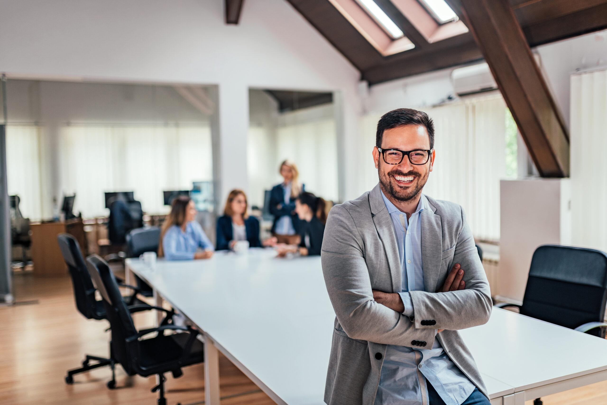 A smiling business owner stands in front of his employees as they fill out applications to become credit union members.