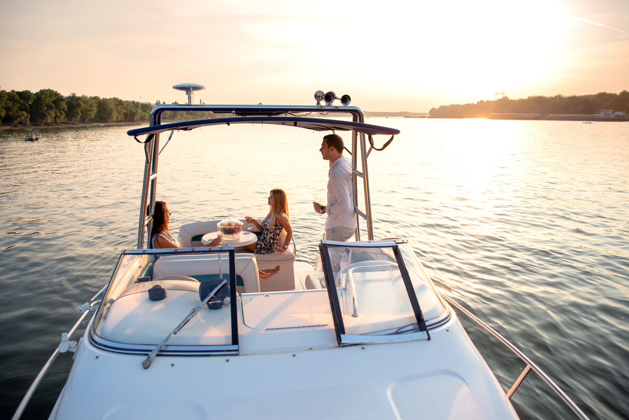 Three friends enjoy the sunset while aboard a boat in a lake