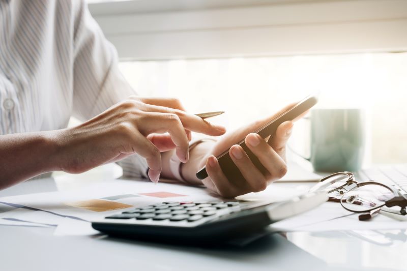 Person using calculator and phone<br />
